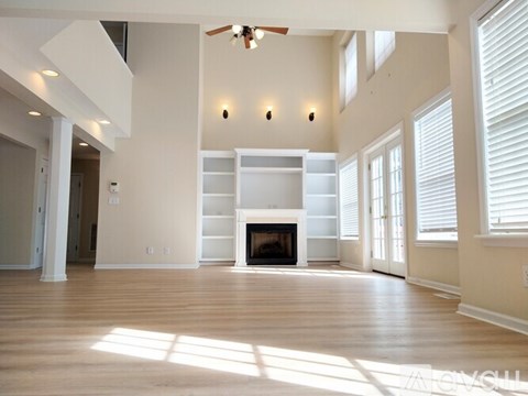 A large, empty living room with a fireplace and built-in shelves.