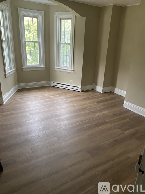 A room with wooden floors and two windows.