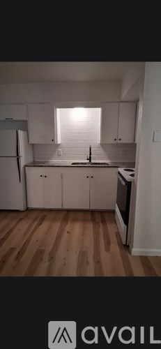 A kitchen with white cabinets and a wooden floor.