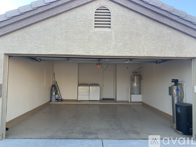 A garage with a white wall and a black trash can.