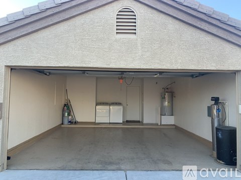 A garage with a white wall and a black trash can.