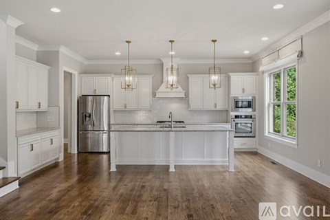 A modern kitchen with white cabinets and a wooden floor.