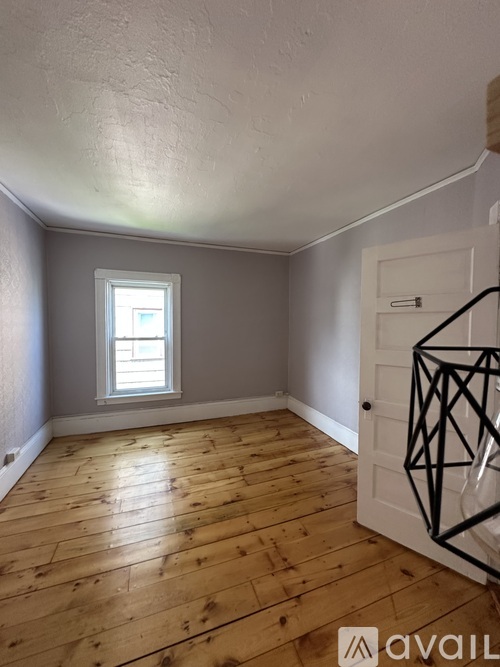 A room with wooden flooring and a window.