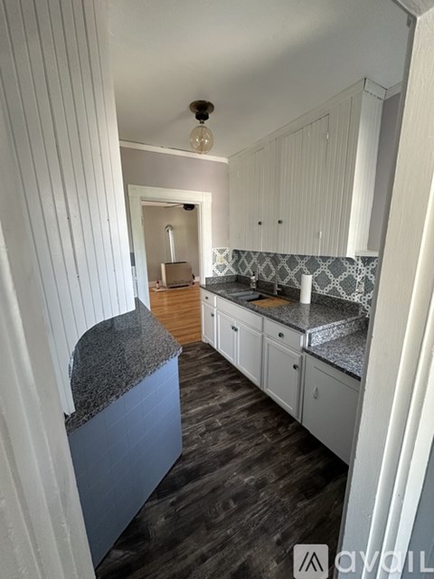 A kitchen with a granite countertop and white cabinets.