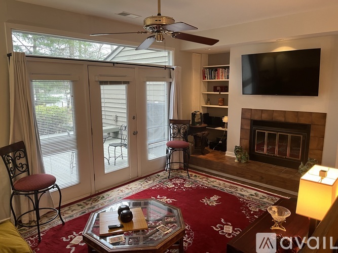 A living room with a fireplace, a television, and a ceiling fan.