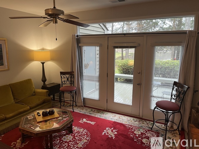 A living room with a green couch, a coffee table, and a ceiling fan.