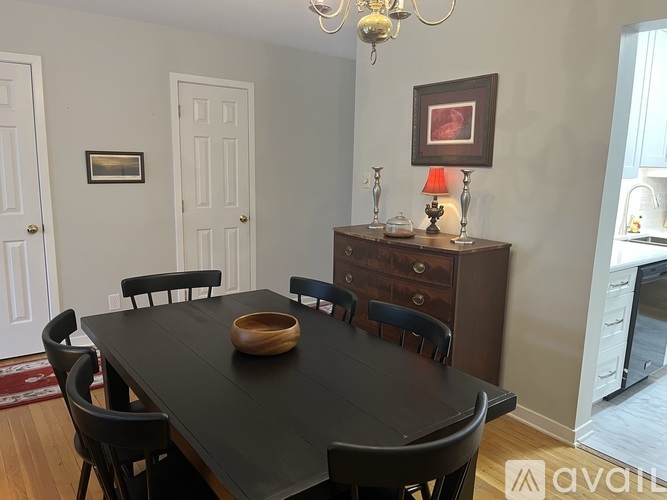 A dining room with a black table and chairs.