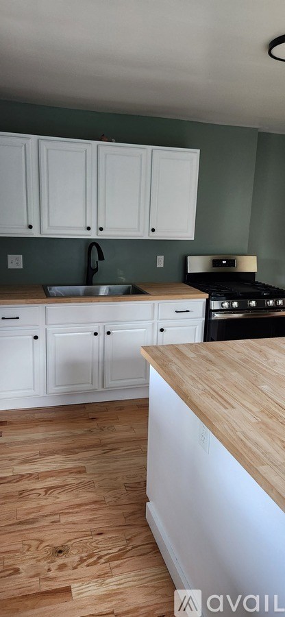 A kitchen with white cabinets and a wooden countertop.