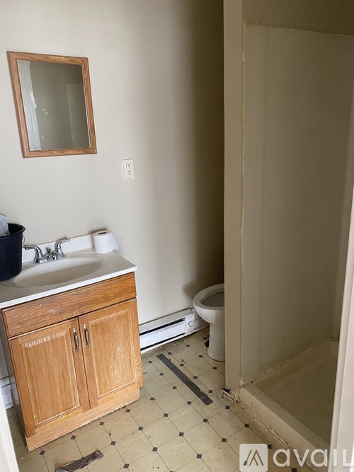 A person in a blue hoodie is standing in a kitchen with brown cabinets and a marble countertop.