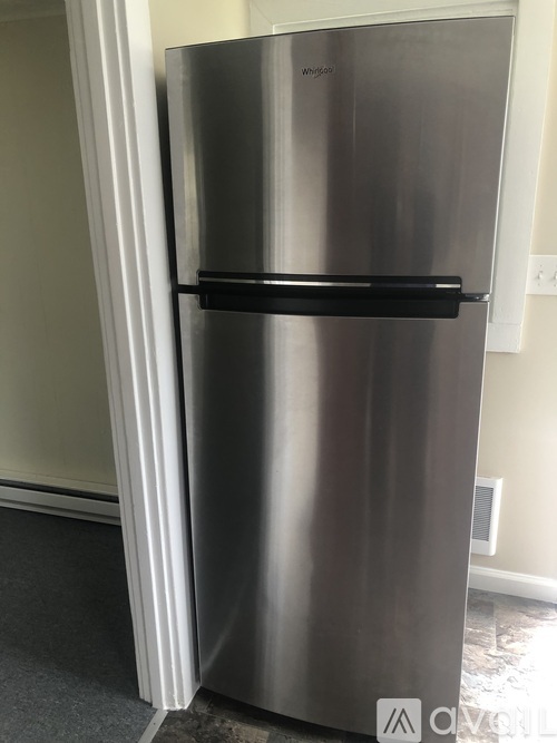 A silver fridge with a black handle sits in a room.