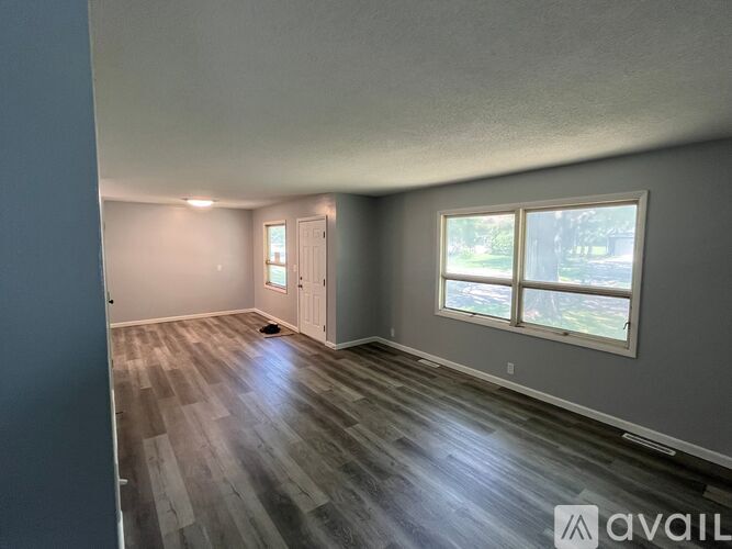 A room with wooden flooring and a window showing greenery outside.