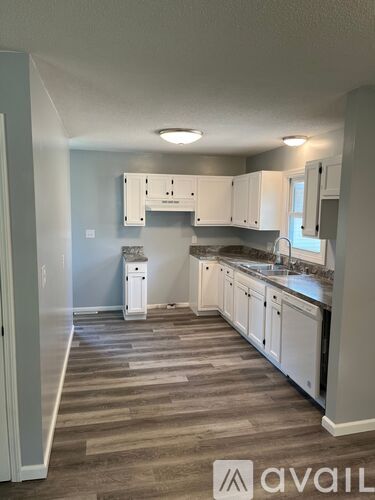 A kitchen with white cabinets and a wooden floor.