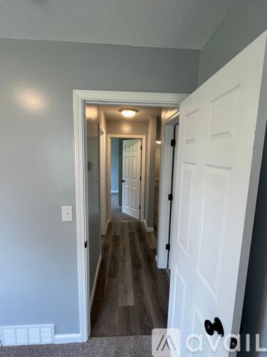 A hallway with a white door on the right and a white wall on the left.