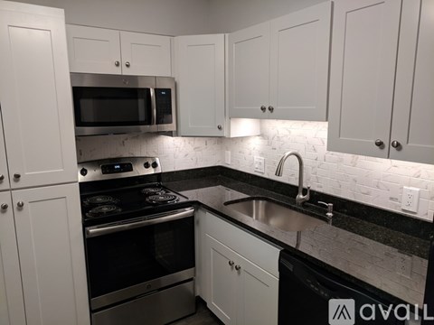 A kitchen with white cabinets and black countertops.