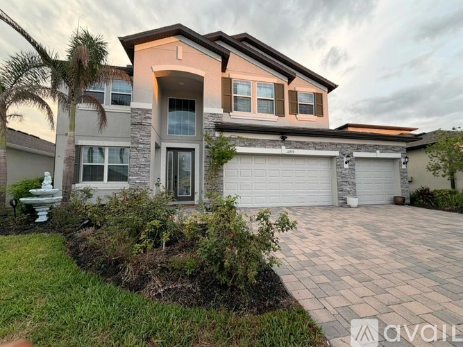 A modern house with a driveway and landscaping in front.