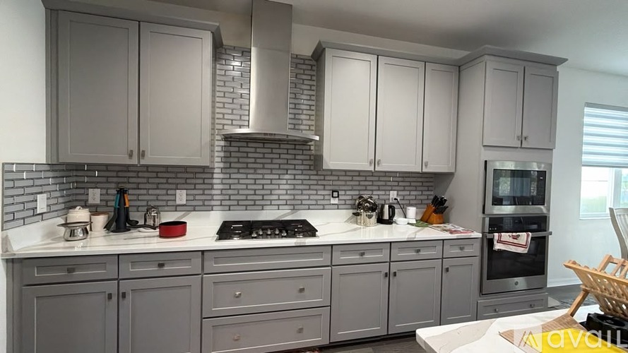 A kitchen with grey cabinets and a white countertop.