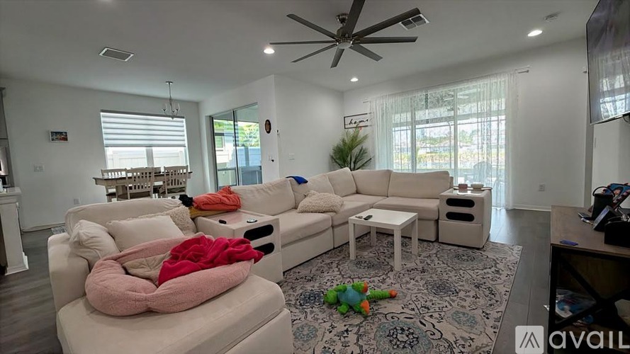 A living room with a white couch and a pink blanket on it.