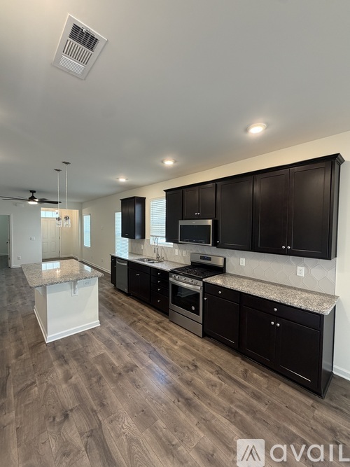 A kitchen with black cabinets and a white island.