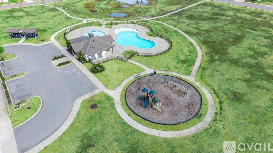 A playground with a blue pool and a slide is surrounded by a green lawn.