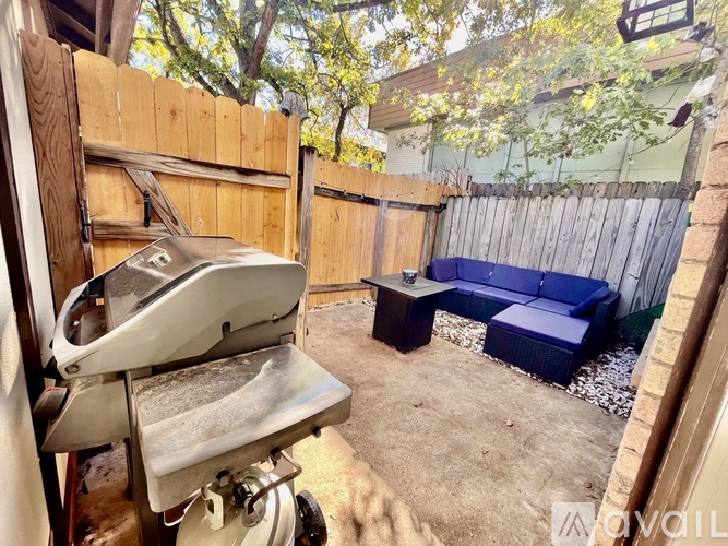 A treadmill is in a backyard with a blue couch and a table.