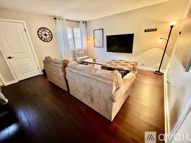 A living room with a couch, a clock, a television, and a lamp.
