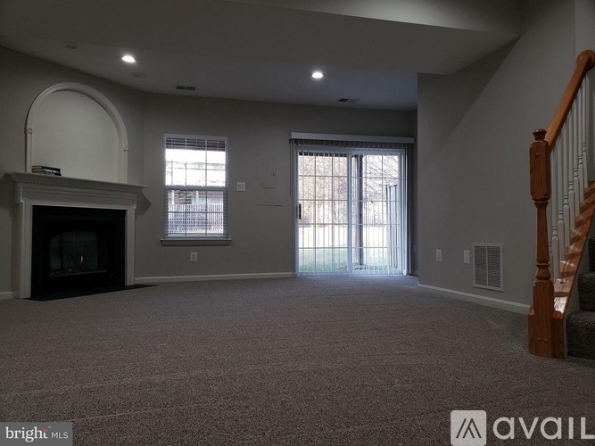 A spacious living room with a fireplace and a carpeted floor.