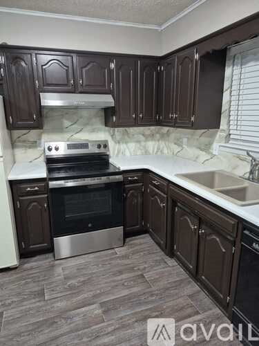 A kitchen with dark brown cabinets and a stainless steel oven.