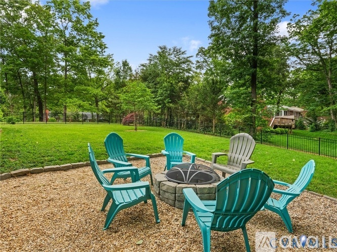 A set of green chairs are arranged around a fire pit.