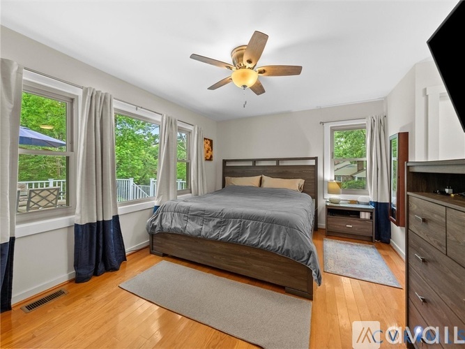 A bedroom with a bed, dresser, and a ceiling fan.