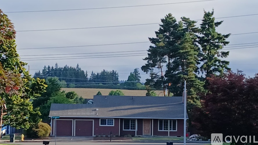 A house with a garage is in the foreground with trees and a hill in the background.