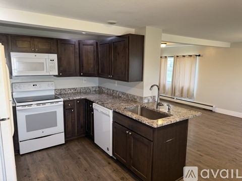 A kitchen with dark wood cabinets and granite countertops.