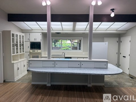 A kitchen with a large island in the middle and a sink under the window.