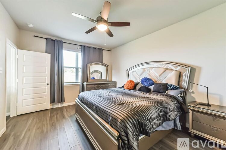 A bedroom with a large bed, a ceiling fan, and a window with curtains.