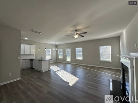 A spacious living room with a fireplace and a kitchen area in the background.