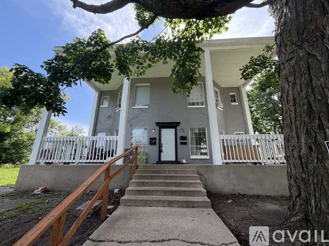 A house with a front porch and a tree in front.