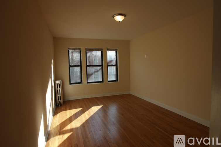 A room with wooden floors and a window with a view of trees outside.