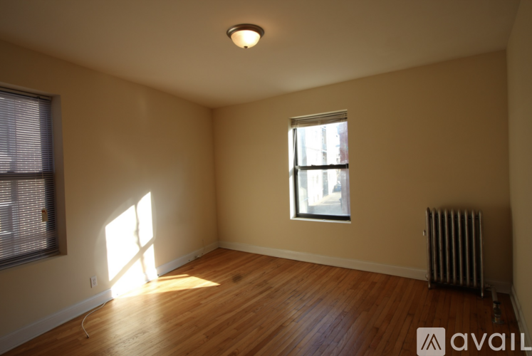 A room with wooden floors and a window letting in sunlight.