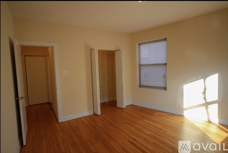 A room with wooden floors and a window with sunlight coming through.