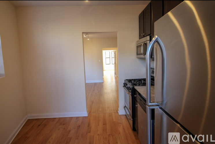 A kitchen with a stainless steel refrigerator and wooden floors.