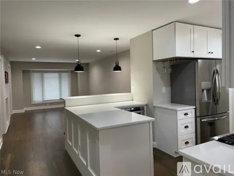 A kitchen with white cabinets and a wooden floor.
