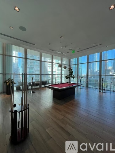 A room with a pool table and a view of the city.