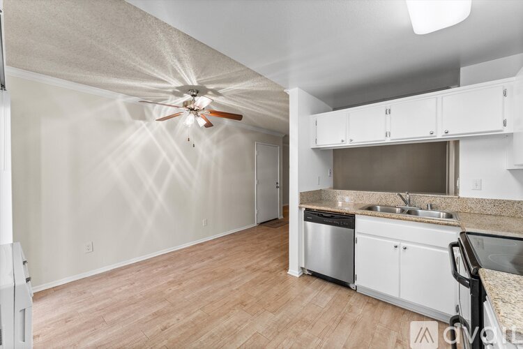 A kitchen with white cabinets and a fan on the ceiling.