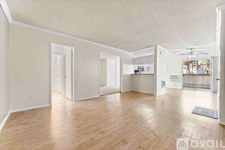 A spacious living room with hardwood floors and white walls.