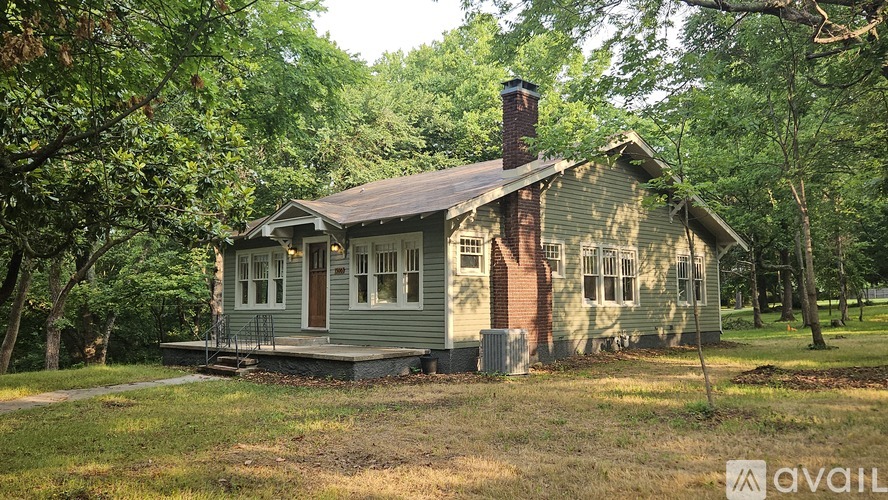 A small house with a brown roof is surrounded by trees.