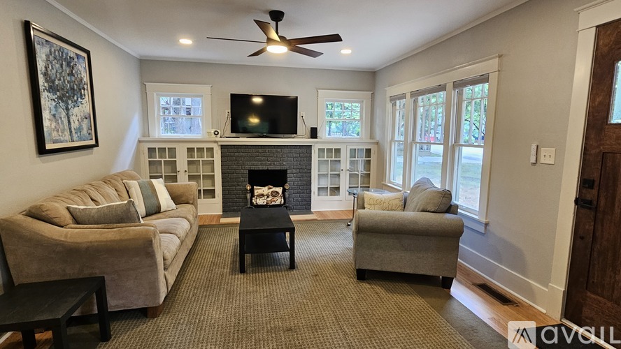 A living room with a fireplace, a couch, a chair, and a television.