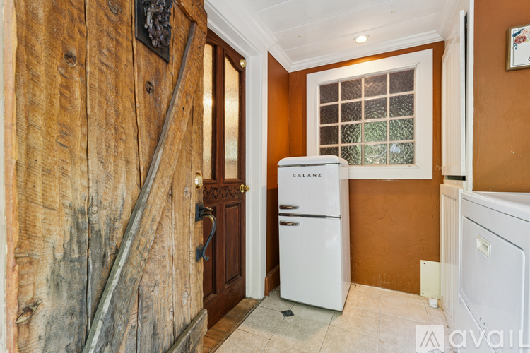 A white refrigerator sits in a kitchen with wooden walls.