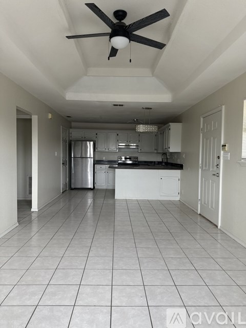 A kitchen with white cabinets and a fan on the ceiling.