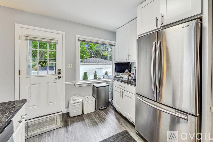 A kitchen with a stainless steel refrigerator and white cabinets.
