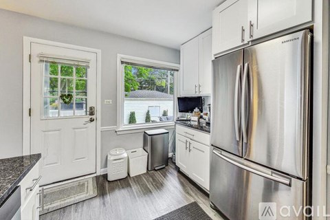 A kitchen with a stainless steel refrigerator and white cabinets.