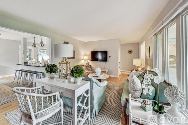 A living room with a white couch and a white coffee table with a vase of flowers on it.